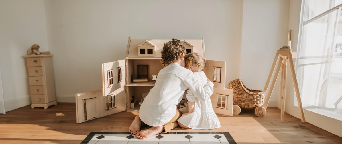 Broertje en zusje spelen samen met een poppenhuis.