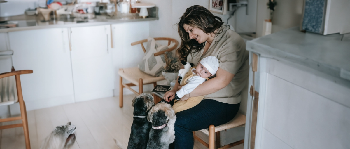 Moeder en baby spelen met twee hondjes thuis.