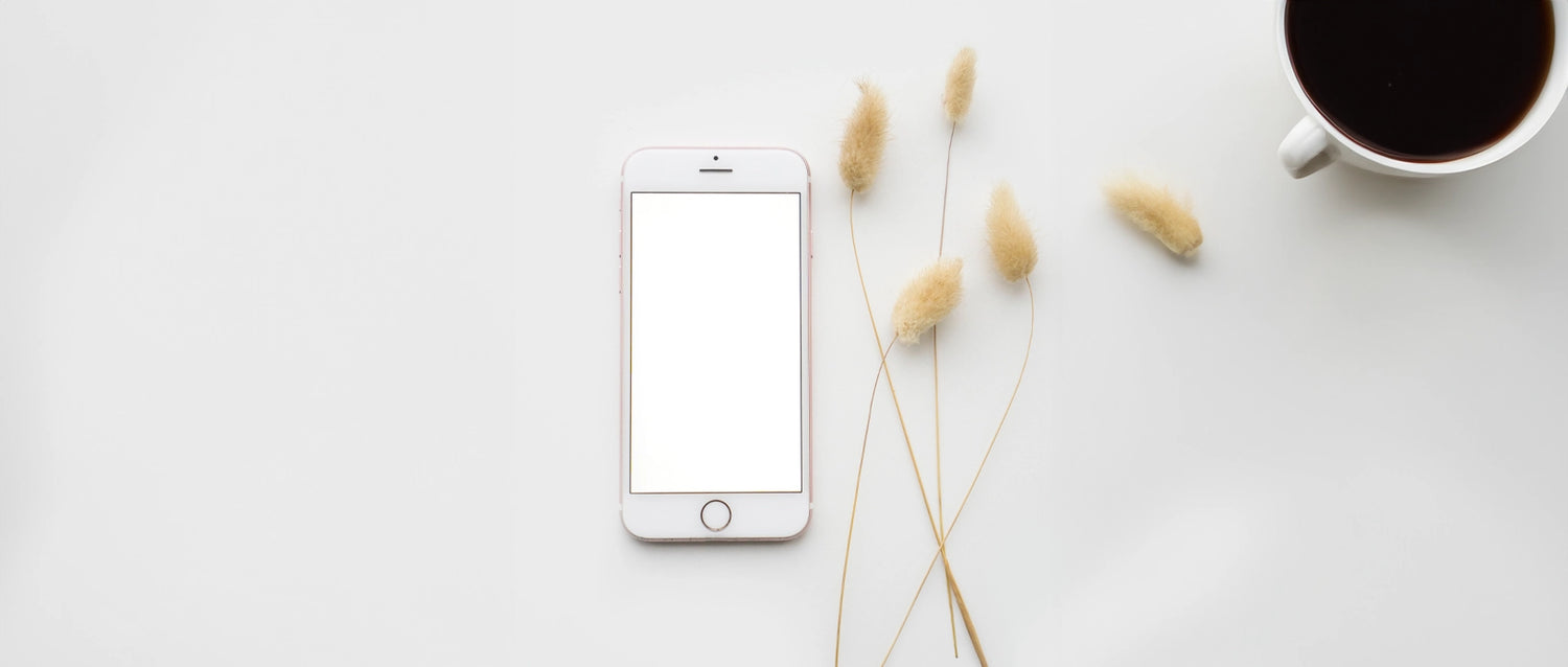 Telefoon en kop koffie op tafel.
