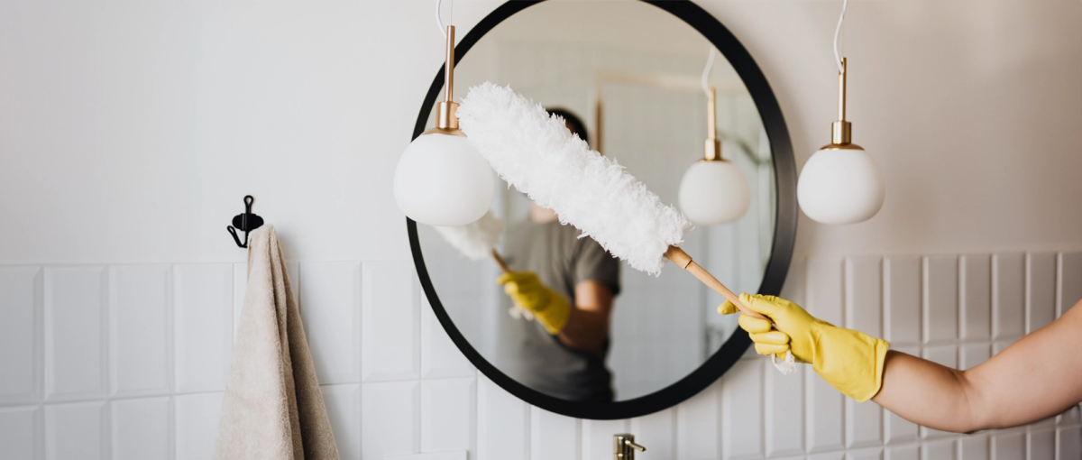 Vrouw afstoft lampen en spiegel.