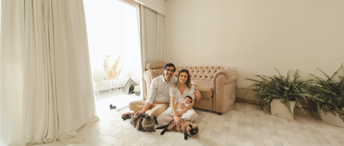 Een gezin met een baby en twee katten in de woonkamer.